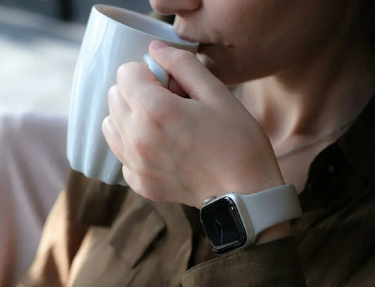 Apple Watch mit Zifferblatt am Handgelenk beim Kaffeetrinken