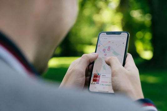 Person hält ein iPhone mit geöffneter Karten-App in der Hand.